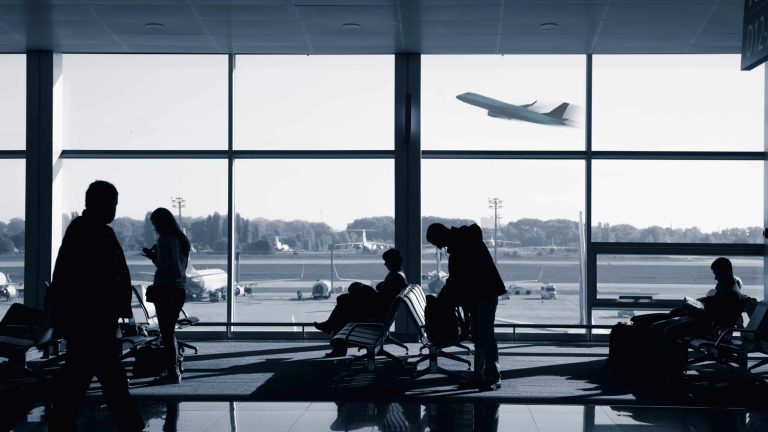 Real People waiting for the flight inside airport terminal lounge, blue toned